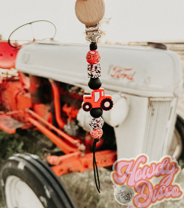 Pacifer clip made out of silicone beads, In the pattern of Round red bandna print, Cowprint hexagon shape bead, Black round bead, red tractor focal bead, black round bead, cow print hexagon print bead, round red bandana print bead
